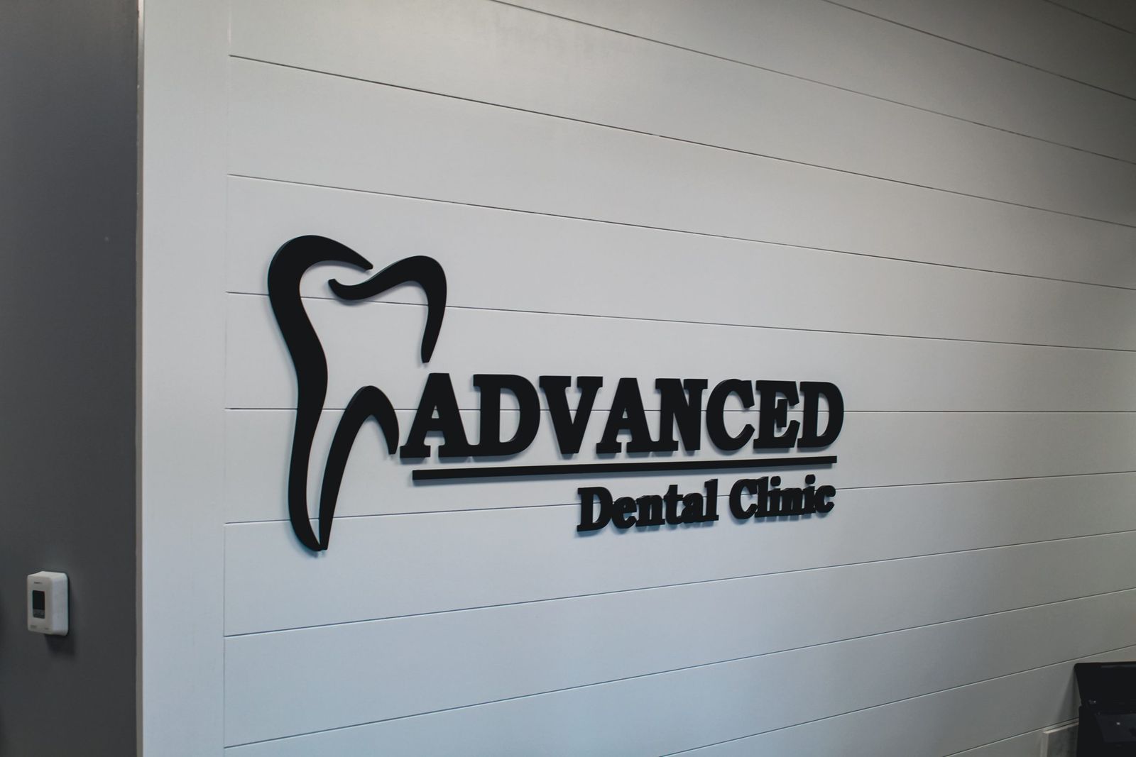 The Advanced Dental Clinic sign on a white shiplap wall